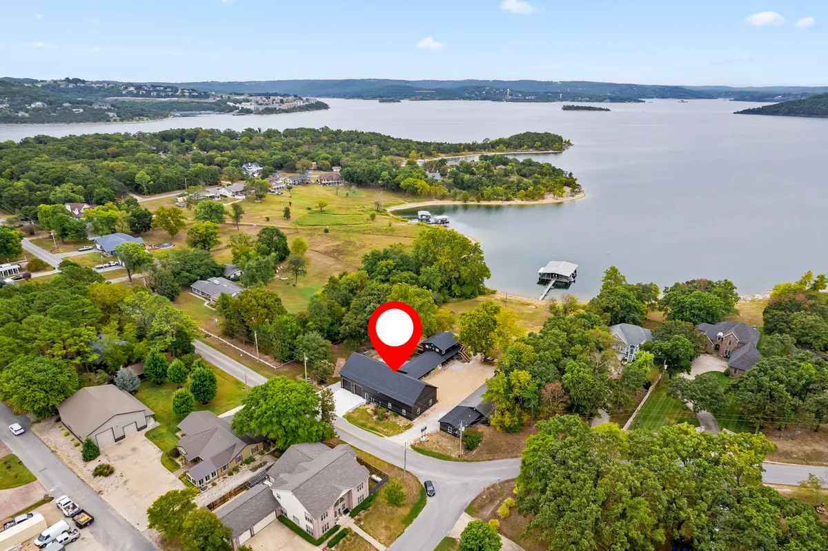 A tranquil exterior view of the resort’s lakeside location, with a house overlooking the water, surrounded by greenery and docks extending out onto the lake. The image conveys an inviting space perfect for group outdoor activities such as boating, fishing, and relaxing by the water.