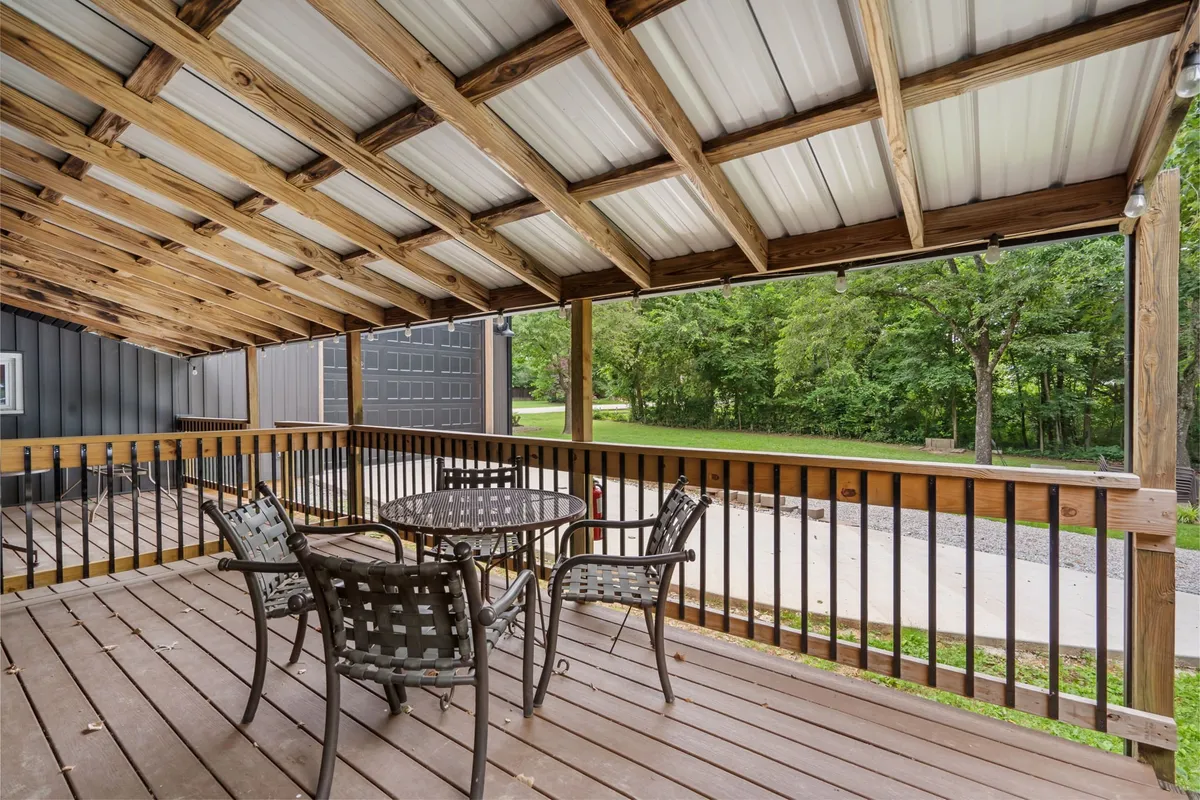 An inviting exterior scene of a wooden deck set for outdoor dining, surrounded by greenery. The outdoor table and chairs invite group meals and gatherings, exemplifying the shared amenities mentioned in the section.