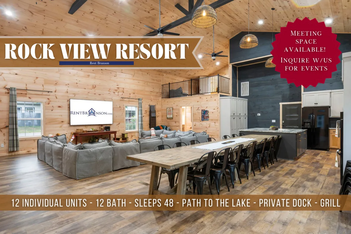A spacious, inviting gathering room featuring a large sectional sofa, a prominent dining table, an open kitchen area, exposed wooden beams, and expansive windows that let in warm, natural light. The room feels welcoming and communal, set up for group events and relaxing moments.