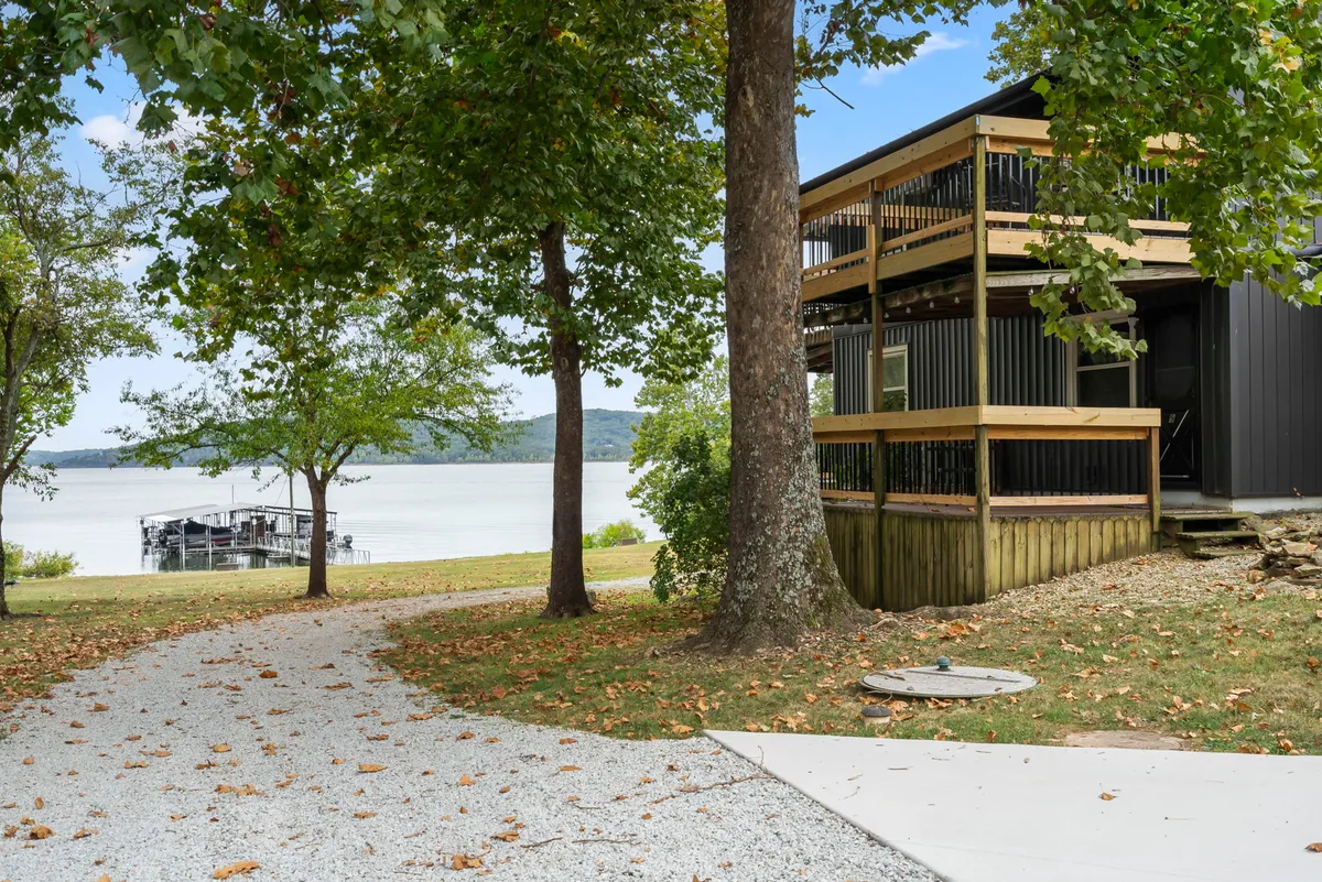 A peaceful view showing a pathway leading to a wooden deck overlooking the water, with trees framing the scene. The deck itself offers space for outdoor relaxation and is situated close to the shoreline, hinting at easy access to a private dock for lake activities.